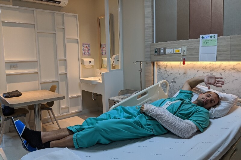 man laying in Cambodia hospital bed after surgery