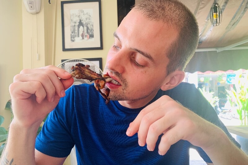 man eating fried frog Cambodian food