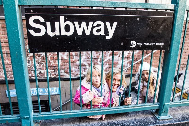 girls posing under subway sign on stairs