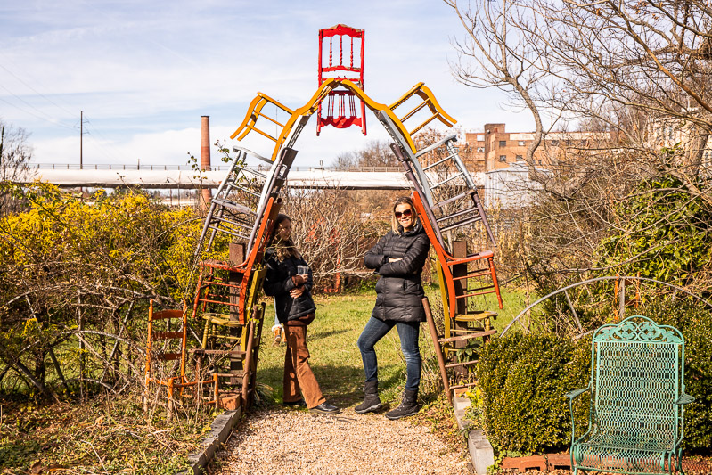 mother and daughter standing at chair arch sculpture