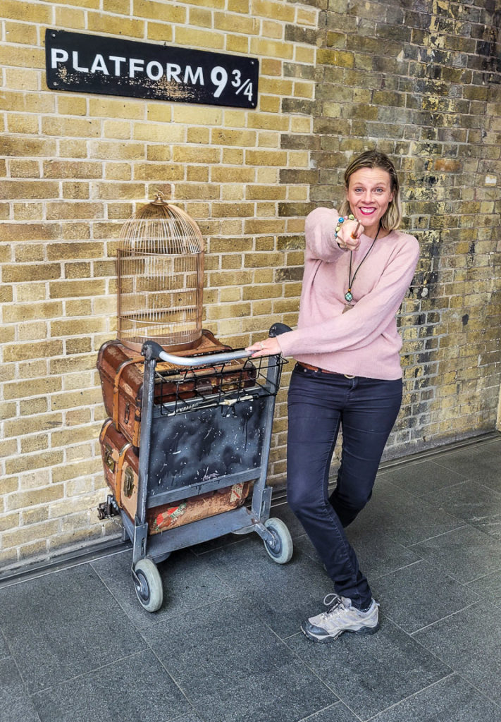 woman holding wand at cart going into wall at Platform 9 3/4, Kings Cross Station, London