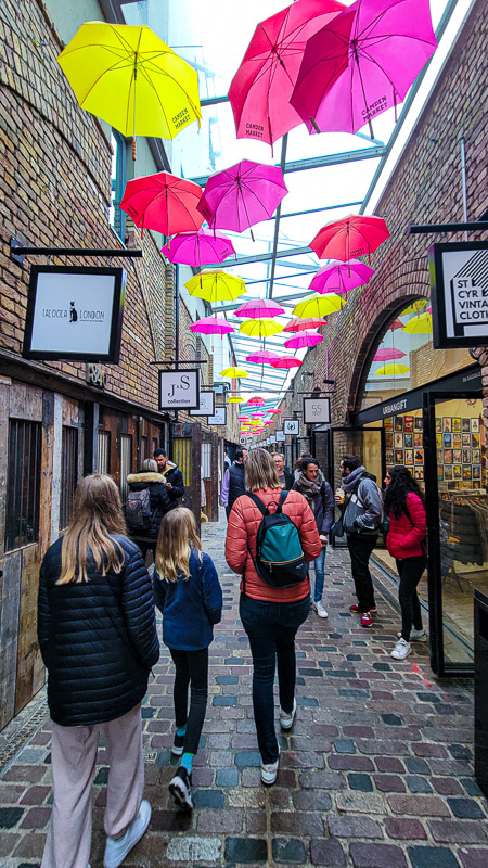 people walking through camden markets under colorful umbrellas