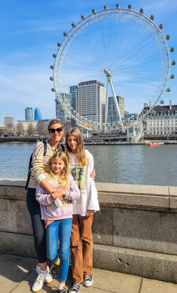 people standing on a bridge in front of the london eye