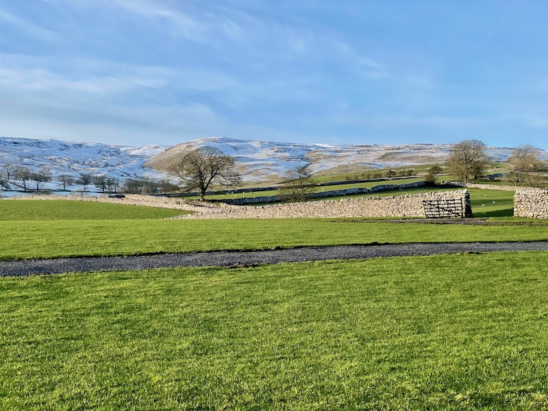 green English countryside with rolling snow covered hills in the background