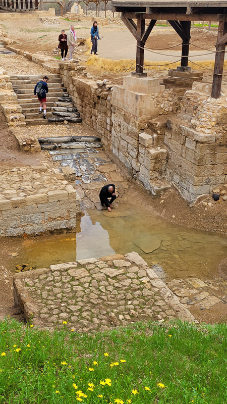 man at the edge of the water at jesus baptism pool