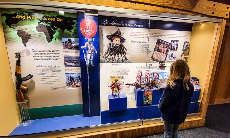 a girl standing in front of a museum display