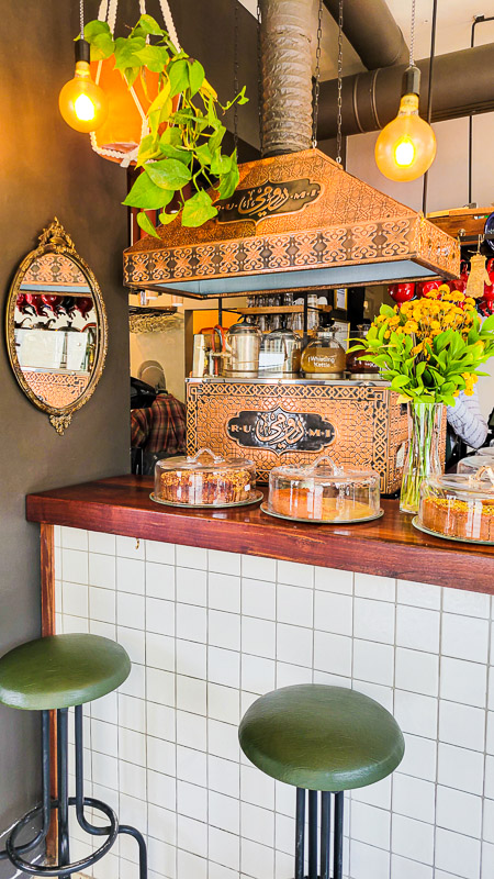 stools at a counter with coffee machine and cake