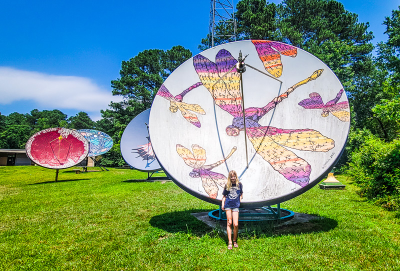 girls tanding in front of satellites covered in murals