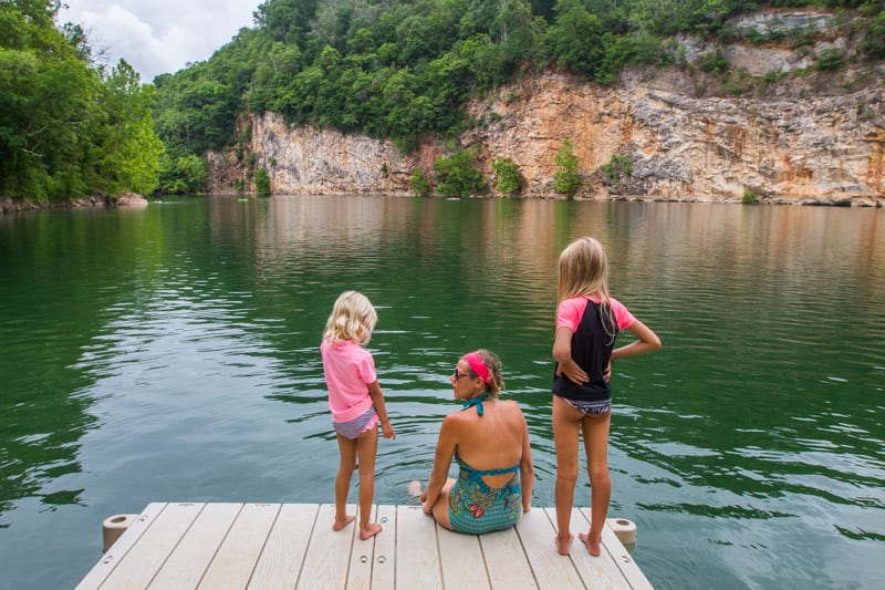 woman and two children sitting at edge of lake