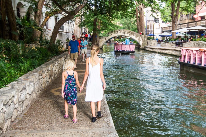 kalyra and savannah holding hands walking along san Antonio river