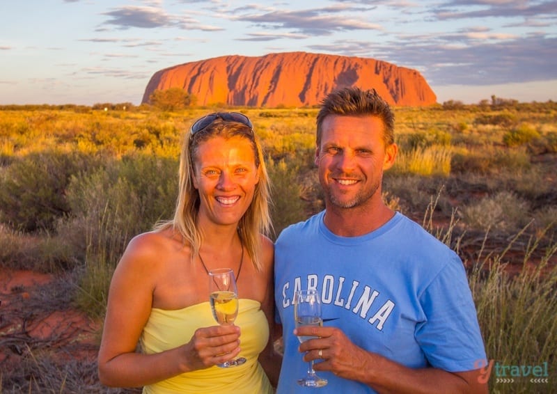 caz and craig drinking champange at sunset in front of Uluru