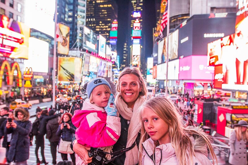 woman and two girls posing in times square