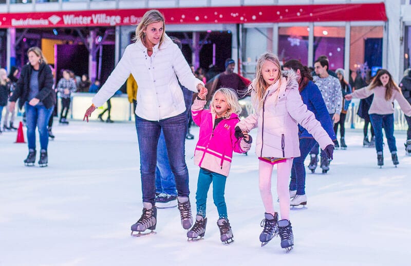 woman and girls holding hands Ice skating at Bryant Park