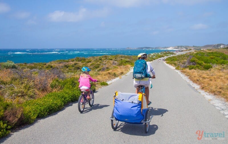 woman and child on bikes on path next to ocean