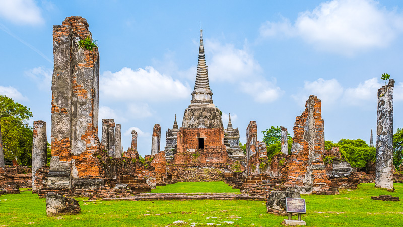 view of crumbling orange brick remains of wat phra si sanphet on green grass