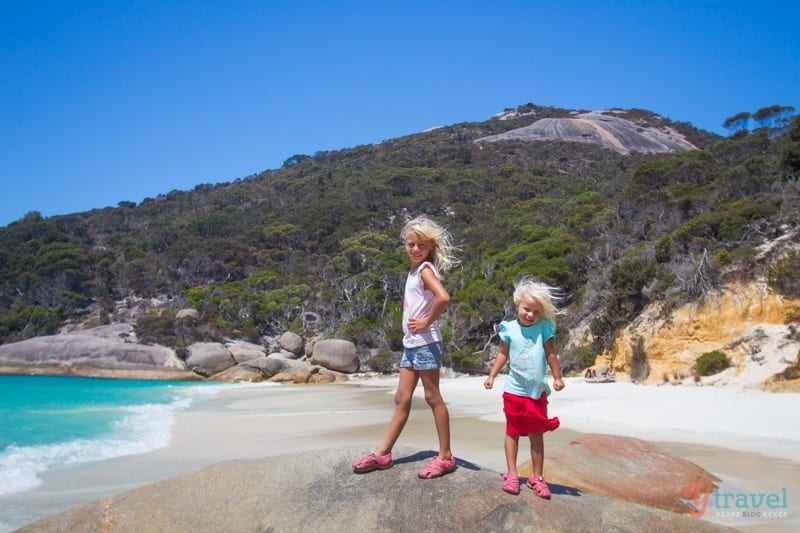 girls standing on rock at the beach