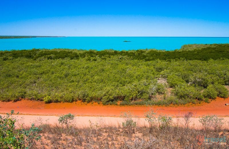 view of red dirt, green marshes, torquoise water and blue sky at broome