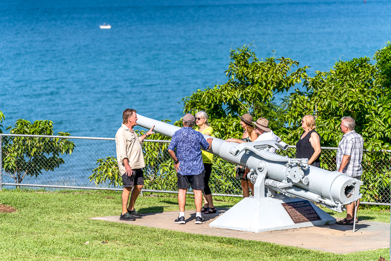 people standing around artillery gun on a cliff face