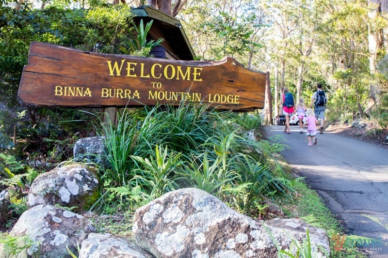 people walking past a sign that reads Binna Burra Mountain Lodge