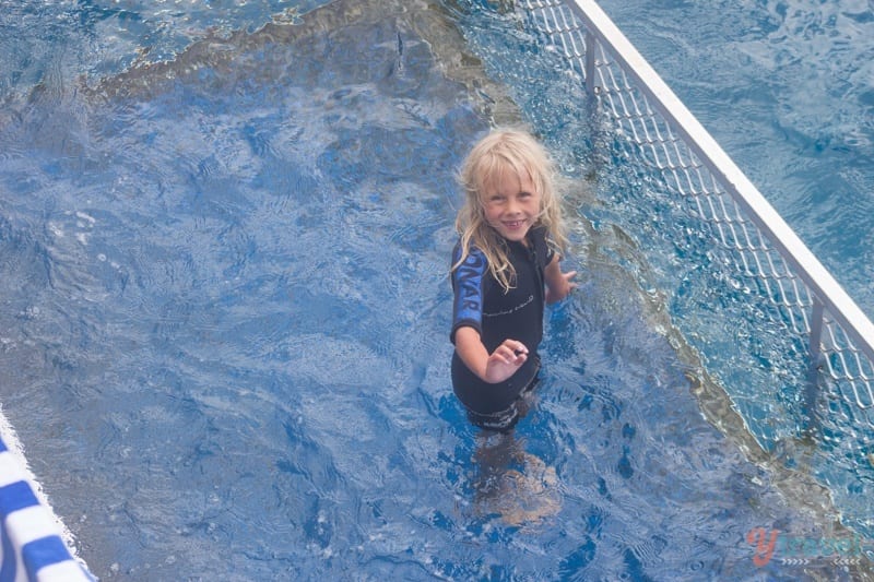 young girl swimming in cage pool in the middle of the ocean