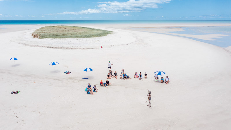 people on a remote island surrounded by white sand