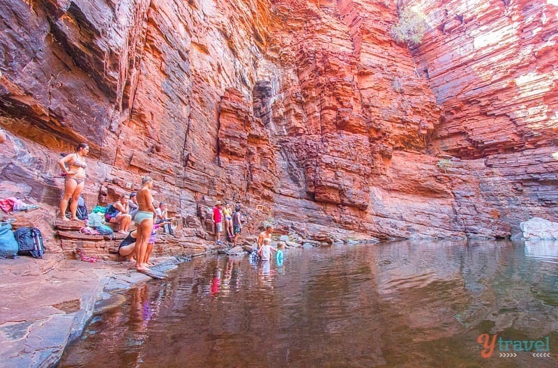 people walking in water through a canyon