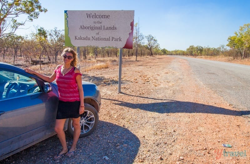 woman standing next to a car in front of a sign