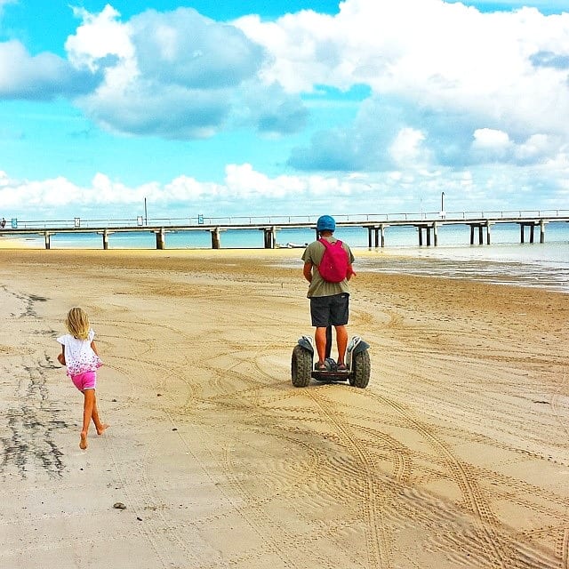 girl chasing man riding segway on the beach