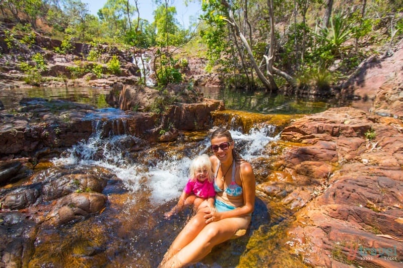 A woman sitting on a rock next to a waterfall