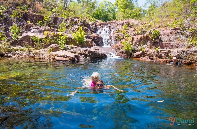 people swimming next to a waterfall