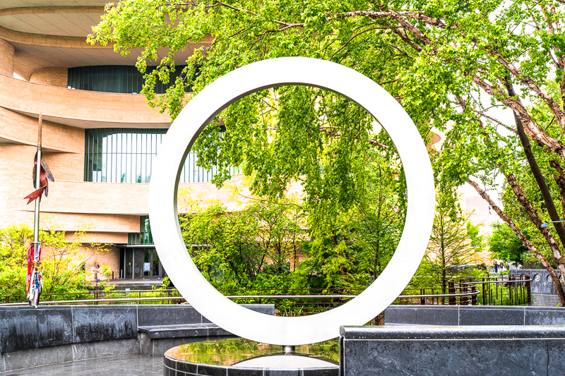 The design "Warriors' Circle of Honor" by Harvey Pratt is a stainless steel circle above a carved stone drum at the National Native American Veterans Memorial.