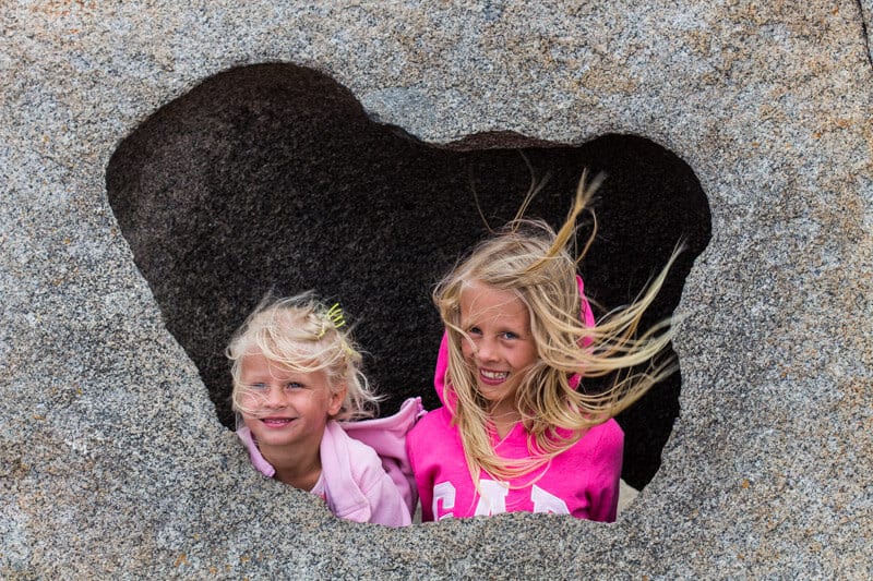 two girls hanging out of a hole in the rock