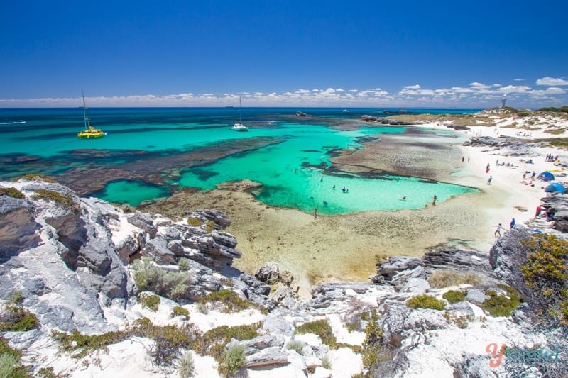 aerial view of curving beach with rocky headland, white sand and awua water