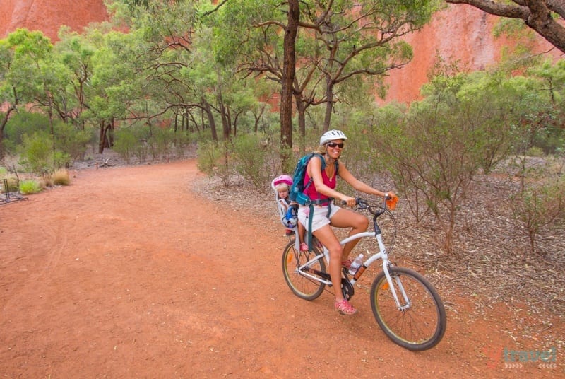 lady riding bike with child on back in desert