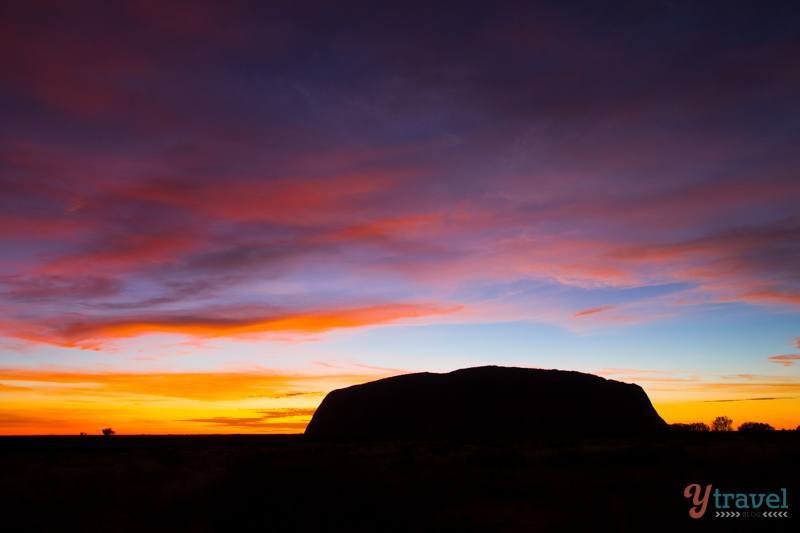 uluru in sillouhette with purple sky