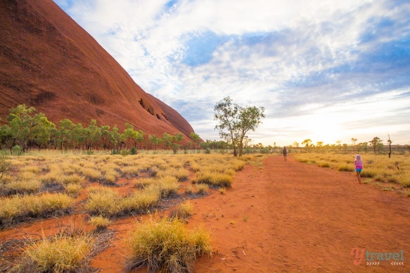 A dirt path next to a big red rock