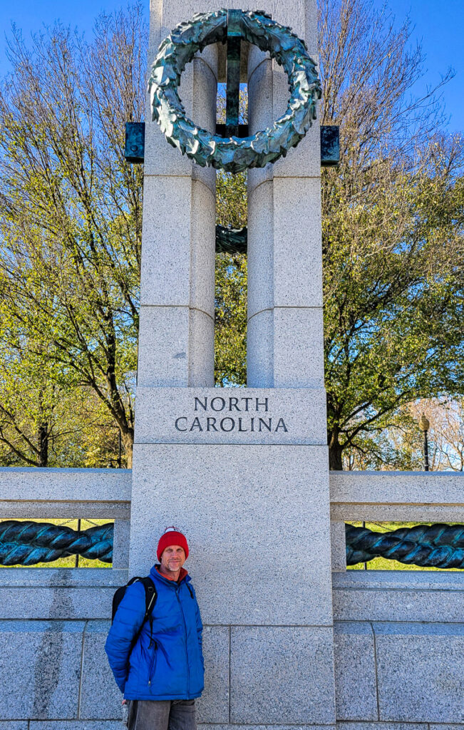 Man standing at a monument Lake and fountain at a war memorial monument in DC