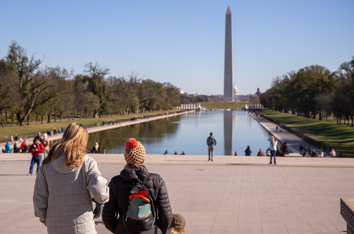 people looking out over the reflection pool and washington monument from the lincoln memorial