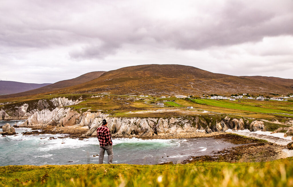 Man standing on a cliff overlooking a bay of water