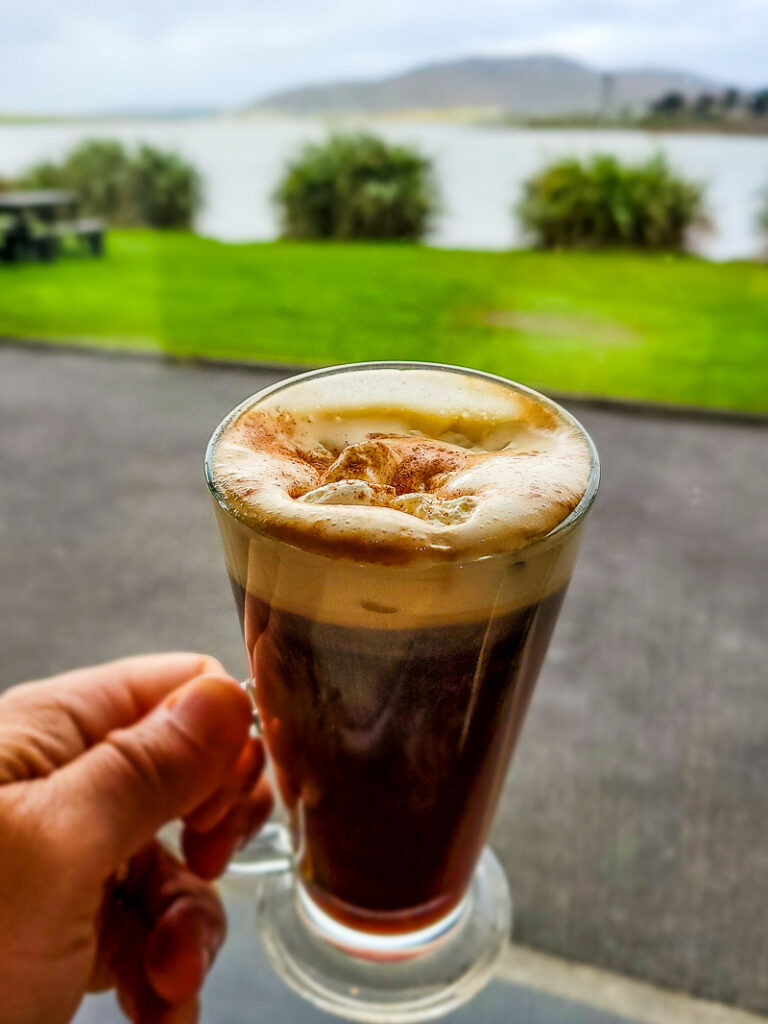 A hand holding up a glass of coffee