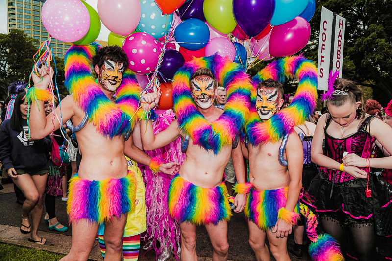 group of gay men in rainbow costumes smiling at camera at Sydney gay and lesbian mardi gras