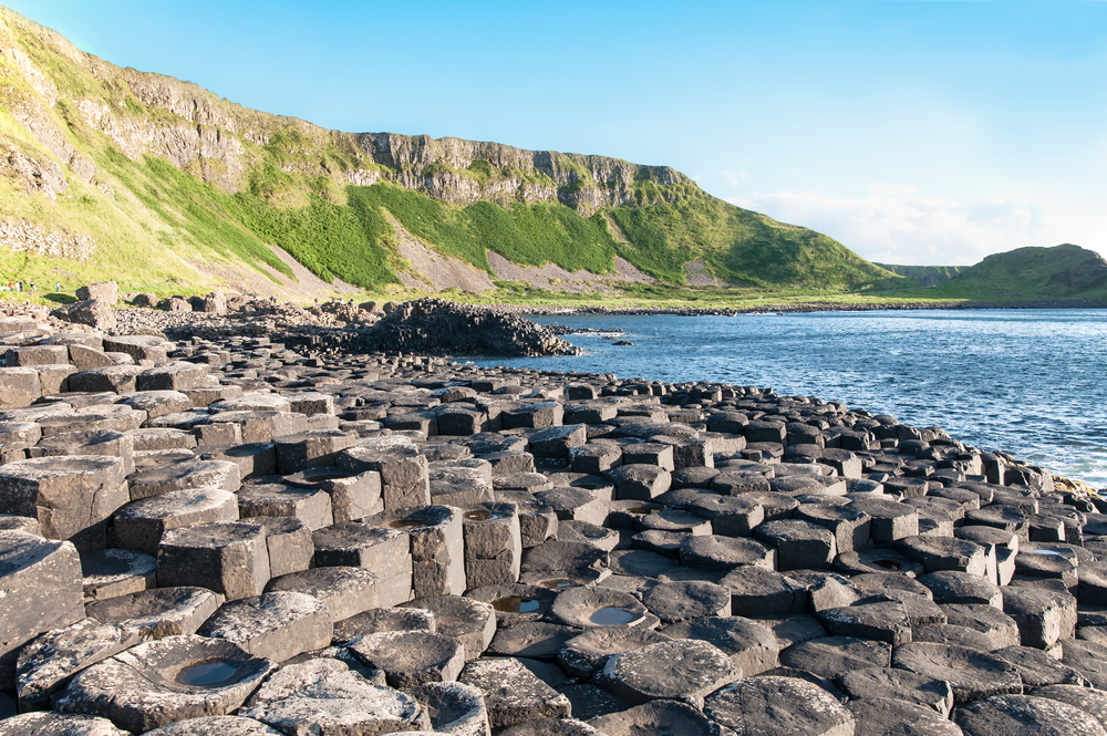 Hexagonal shaped rocks by the ocean with a mountain backdrop