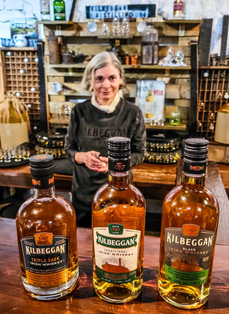 Lady behind a bar and three bottles of Whiskey