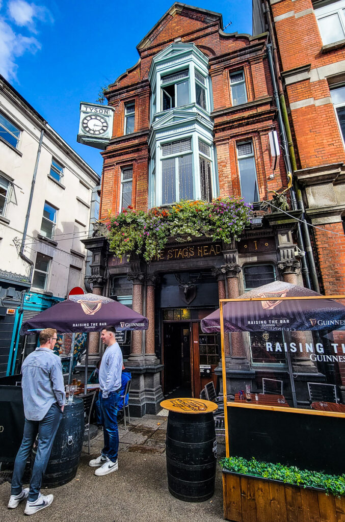 Two men standing outside a pub drinking