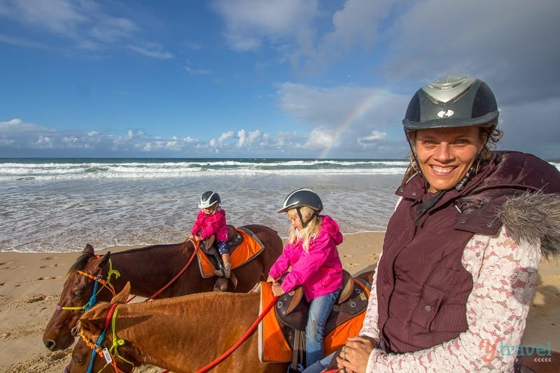 family posing on horses on beach