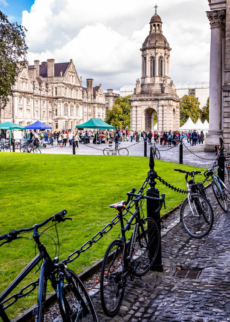 Bikes leaning against a chain fence with a belltower in the background