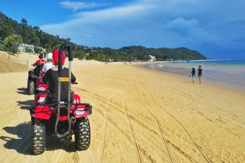 peopel riding quad bikes on beach