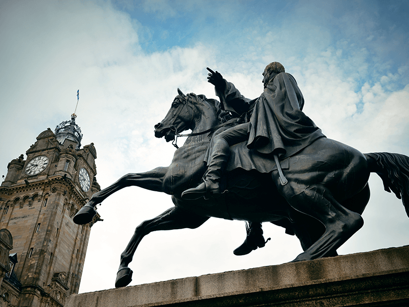 sculpture or man on a horse near clock tower