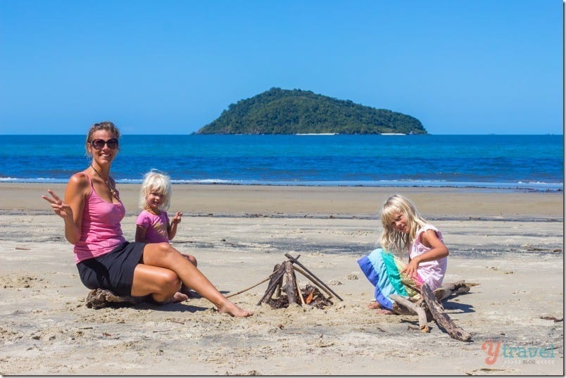 family posing for camera near a fire on beach