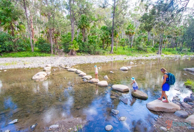 girls walking on rocks over a river